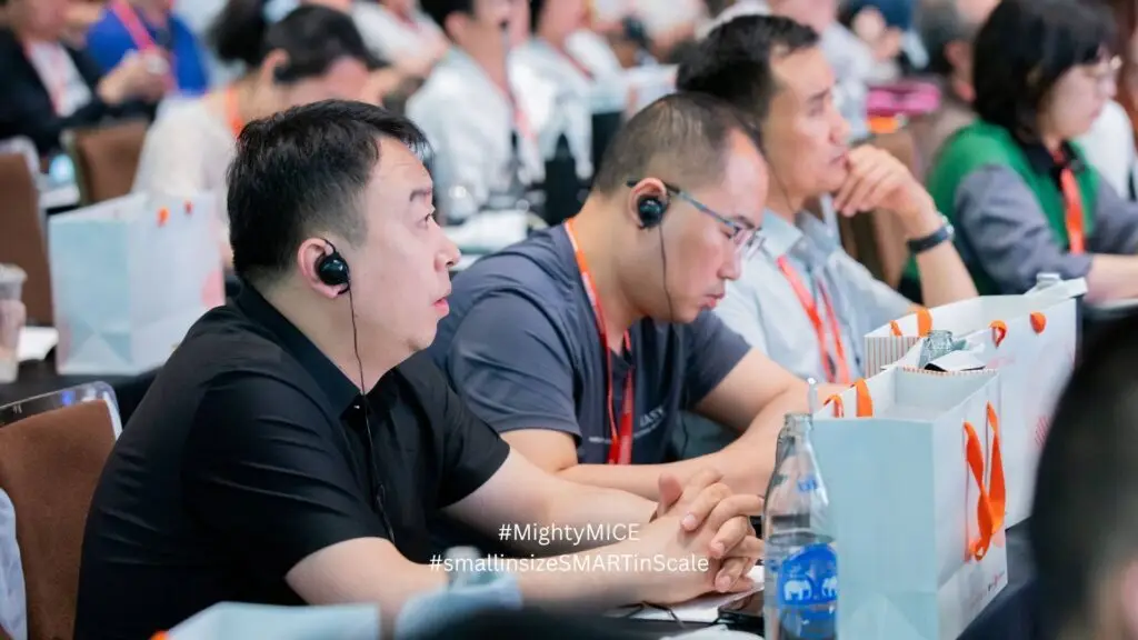 ผู้เข้าประชุมต่างชาติ สวมหูฟังแปลภาษาในงานประชุมนานาชาติที่ใช้ระบบหูฟังแปลภาษามาตรฐานสากล จากไมตี้ ไมซ์
